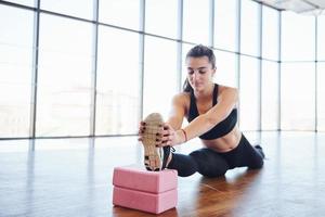 linda mulher desportiva em roupas esportivas fazendo alongamento usando equipamentos no chão foto