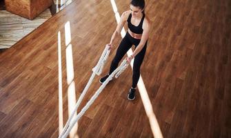 no chão iluminado por feixes de luz. jovem mulher desportiva em roupas esportivas fazendo fitness usando nós foto