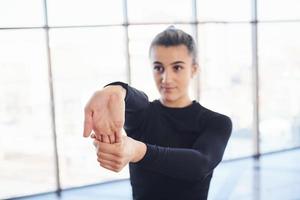 jovem desportiva confiante em roupas esportivas fazendo exercícios de aquecimento para as mãos contra a janela foto