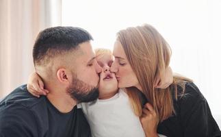 jovem casal com seu filho tem lazer juntos no quarto durante o dia foto