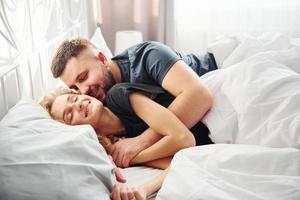 casal jovem bonito deitado na cama e dormindo juntos foto