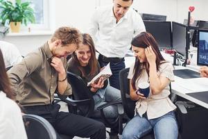 jovens empresários sentados à mesa, conversando e trabalhando juntos no escritório moderno foto