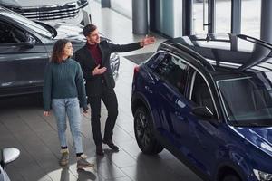 vendedor profissional ajudando jovem escolhendo novo automóvel moderno dentro de casa foto