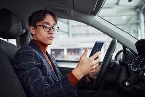 homem de óculos e roupas formais sentado dentro do carro moderno foto