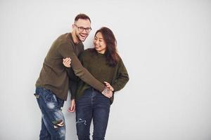 feliz casal multiétnico em roupas casuais está junto dentro de casa no estúdio. cara caucasiano com namorada asiática foto