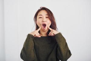 retrato de uma jovem asiática feliz que está dentro de casa no estúdio contra um fundo branco foto