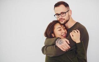 feliz casal multiétnico em roupas casuais está junto dentro de casa no estúdio. cara caucasiano com namorada asiática foto