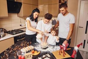 família feliz se diverte na cozinha e preparando comida foto