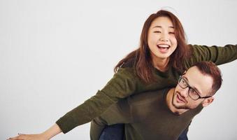 feliz casal multiétnico em roupas casuais se divertem juntos dentro de casa no estúdio. cara caucasiano com namorada asiática foto