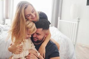 jovem casal com seu filho tem lazer juntos no quarto durante o dia foto