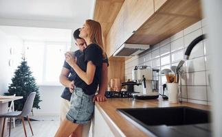 com copo de bebida fresca. manhã para o jovem casal que está dentro de casa na cozinha foto