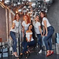 grupo de mulheres alegres que juntas na sala decorada de natal e posando para uma câmera foto