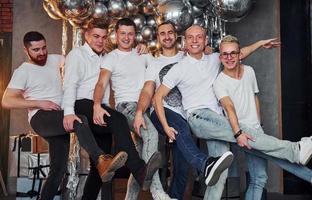 grupo de homens alegres juntos na sala decorada de natal e posando para uma câmera foto