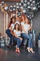 grupo de mulheres alegres que juntas na sala decorada de natal e posando para uma câmera foto