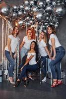 grupo de mulheres alegres que juntas na sala decorada de natal e posando para uma câmera foto