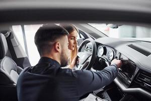 mulher testando carro com ajuda de assistente masculino dentro de casa no salão foto