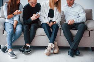 grupo de amigos sentados no sofá com telefones juntos foto