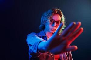 retrato de jovem alternativa em óculos com cabelo verde em luz neon vermelha e azul no estúdio foto