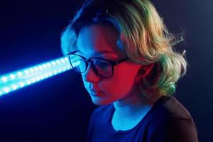 retrato de jovem alternativa em óculos com cabelo verde em luz neon vermelha e azul no estúdio foto