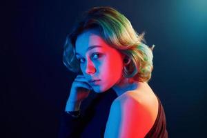 retrato de uma jovem alternativa com cabelo verde em luz neon vermelha e azul no estúdio foto