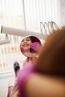 olha para o espelho. menina visitando dentista na clínica. concepção de estomatologia foto