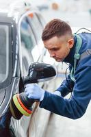 trabalhador masculino em carro novo e moderno de polimento uniforme. concepção de serviço foto