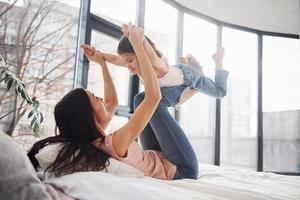 jovem mãe com sua filha passando o fim de semana juntos na cama foto