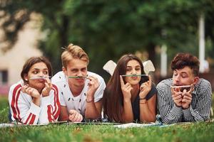 humor lúdico. grupo de jovens estudantes em roupas casuais na grama verde durante o dia foto