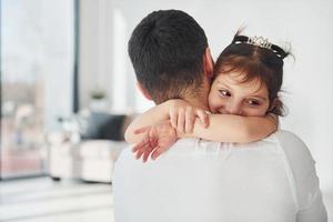 pai feliz com sua filha se abraçando em casa foto