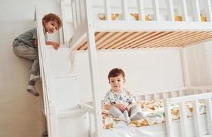 dois garotinhos descansando e se divertindo dentro de casa no quarto juntos foto