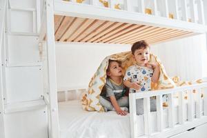 dois garotinhos descansando e se divertindo dentro de casa no quarto juntos foto