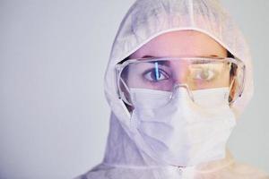 retrato de médica cientista em jaleco, óculos de proteção e máscara foto