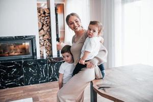jovem mãe com seus filhos juntos dentro de casa em casa no fim de semana foto