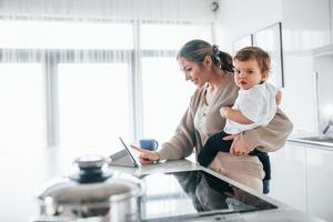 mãe blogueira feminina com seu filho juntos dentro de casa no fim de semana usando tablet foto