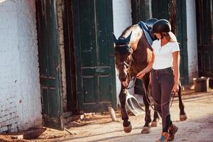 amazona de uniforme e capacete protetor preto com seu cavalo foto