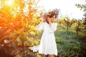 mulher jovem e bonita com coroa de flores no jardim foto