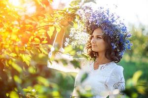 mulher jovem e bonita com coroa de flores no jardim foto