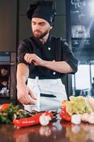 cozinheiro profissional jovem chef de uniforme tem um dia agitado na cozinha foto