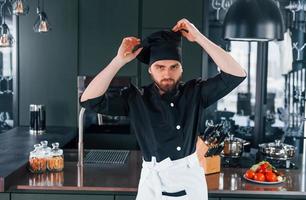 retrato de cozinheiro profissional jovem chef de uniforme que posando para a câmera na cozinha foto