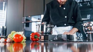 cozinheiro profissional jovem chef de uniforme tem um dia agitado na cozinha foto