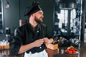 retrato de cozinheiro profissional jovem chef de uniforme que posando para a câmera na cozinha foto