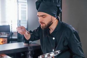 cozinheiro profissional jovem chef de uniforme trabalhando na cozinha foto