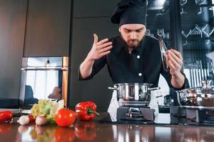 cozinheiro profissional jovem chef de uniforme tem um dia agitado na cozinha foto