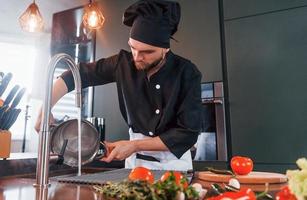 cozinheiro profissional jovem chef de uniforme trabalhando na cozinha foto