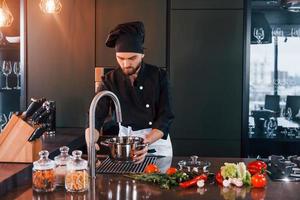 cozinheiro profissional jovem chef de uniforme tem um dia agitado na cozinha foto