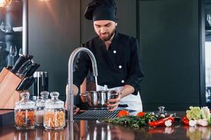 cozinheiro profissional jovem chef de uniforme tem um dia agitado na cozinha foto