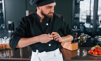 retrato de cozinheiro profissional jovem chef de uniforme que posando para a câmera na cozinha foto