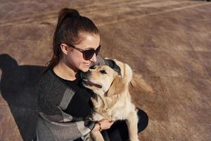 jovem mulher positiva se diverte com seu cachorro quando caminha ao ar livre foto