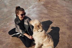 jovem mulher positiva se diverte com seu cachorro quando caminha ao ar livre