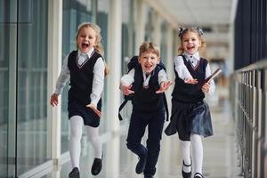 crianças da escola ativas de uniforme correndo juntas no corredor. concepção de educação foto